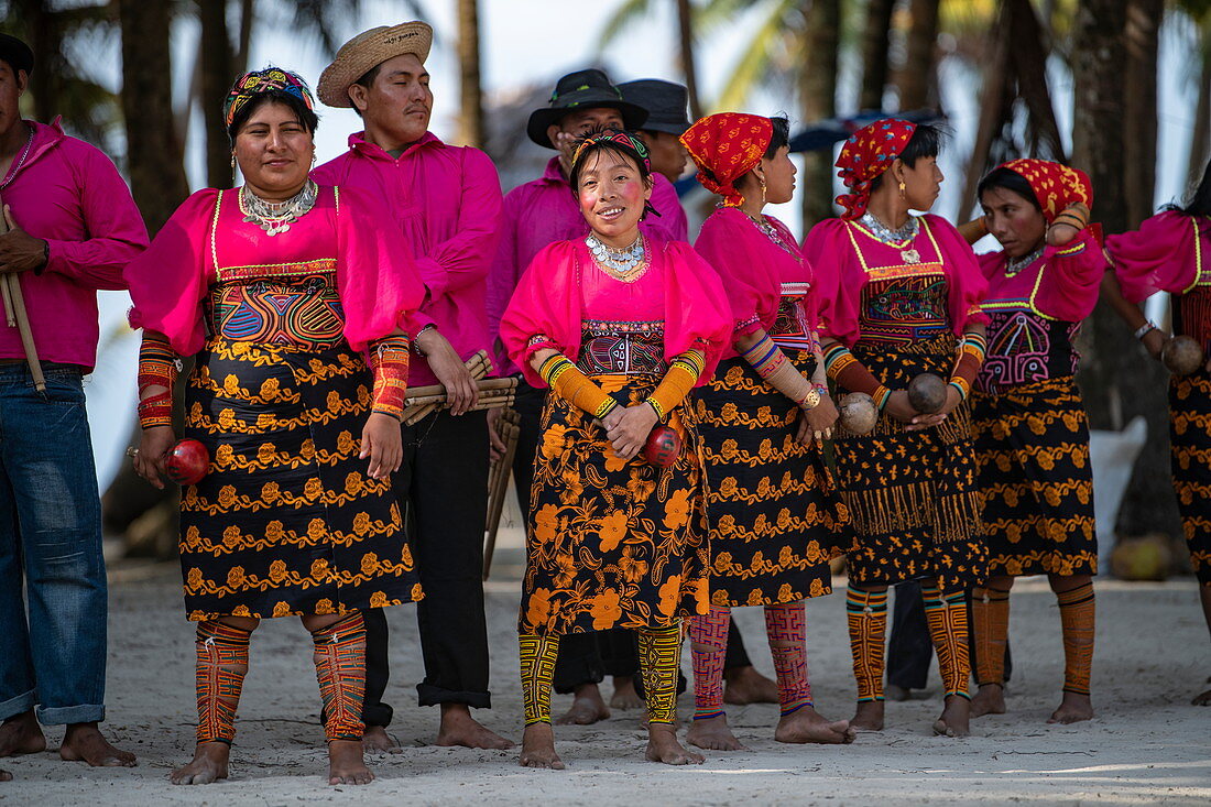 Eine Gruppe von Guna (ehemals Kuna) Ureinwohnern in hellen, traditionellen Kostümen bereitet sich auf einen Folkloretanz vor, Isla Aroma, San Blas Inseln, Panama, Karibik