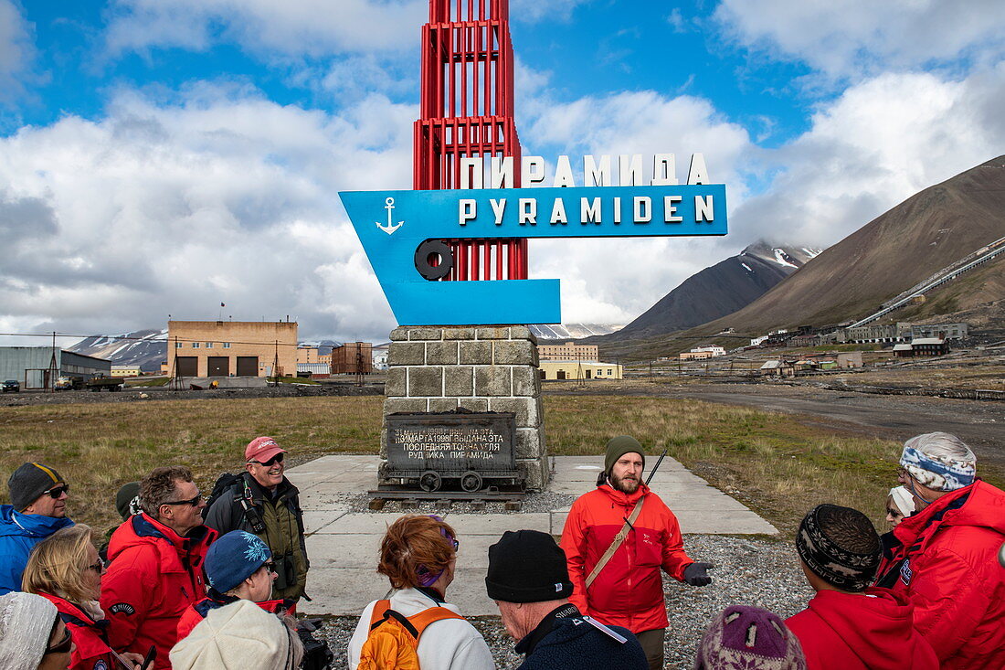 Passengers of the expedition cruise ship Sea Spirit (Poseidon Expeditions) gather around a tour guide at the entrance to the former mining town of Pyramiden, Billefjord, Spitsbergen, Norway, Europe