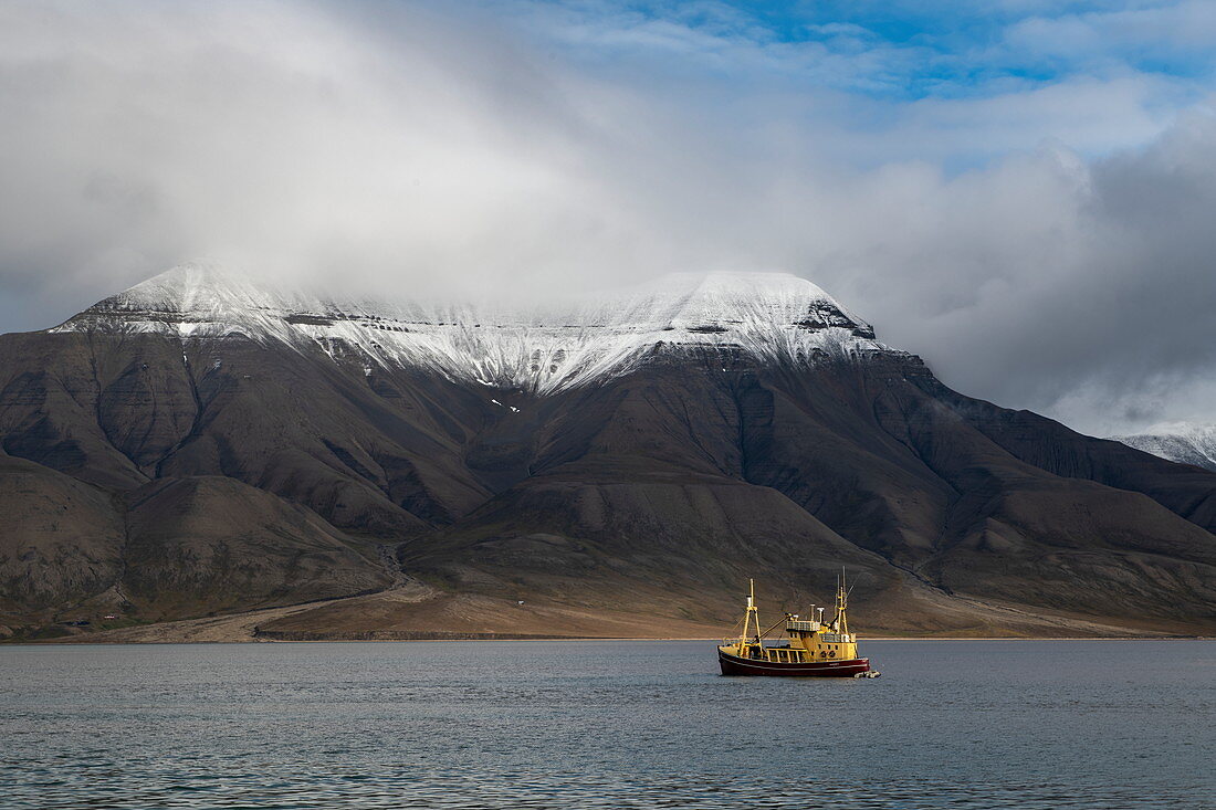 Ein Schiff fährt vor hohen, schneebedeckten Bergen, Spitzbergen, Norwegen, Europa