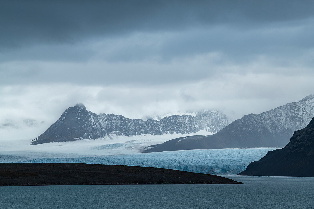 Grafische Szene von schroffen Bergen und einem langen, breiten Gletscher, der sich bis zum Meer erstreckt, Signehamna, Albert-I-Land, Spitzbergen, Norwegen, Europa