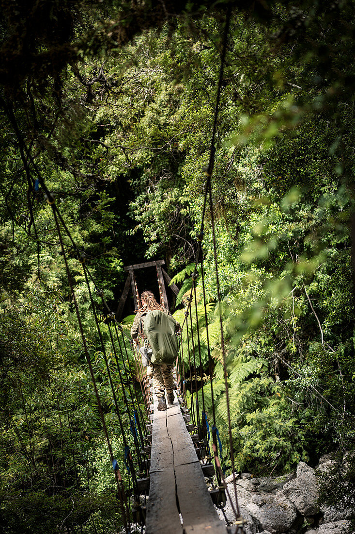 Wanderer überquert Hängeseilbrücke auf dem Weg nach La Junta im Cochamo Tal, Region de los Lagos, Chile, Südamerika