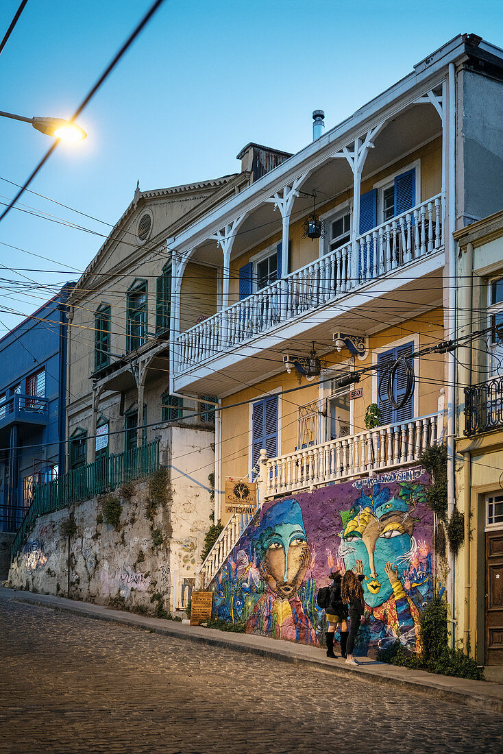 zwei junge Frauen begutachten die Streetart an historischem Gebäude in den Straßen von Valparaiso, Chile, Südamerika