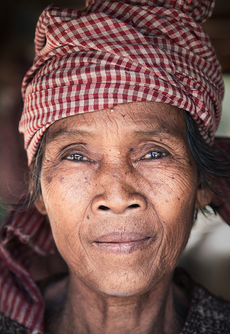 Cambodia - January 18, 2011: A smiling Cambodian woman is wearing a red checkered scarf on her head.