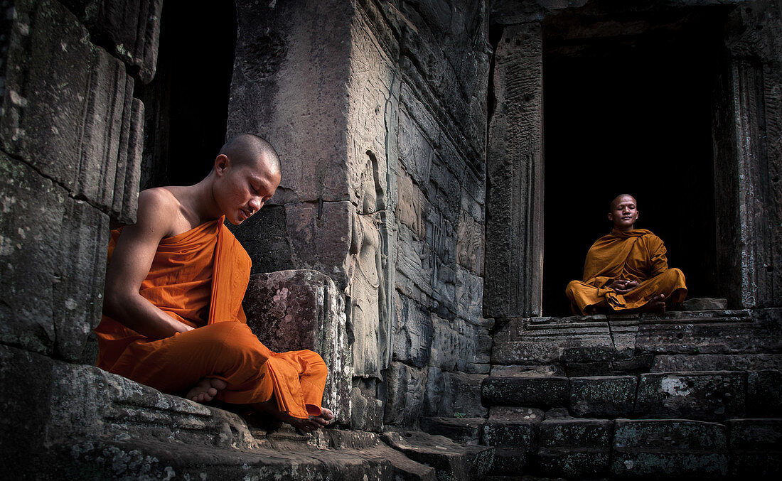 Siem Reap, Kambodscha - 19. Januar 2011: Zwei Mönche in ihrem orangefarbenen Gewand sitzen und meditieren, Angkor Wat Tempelkomplex