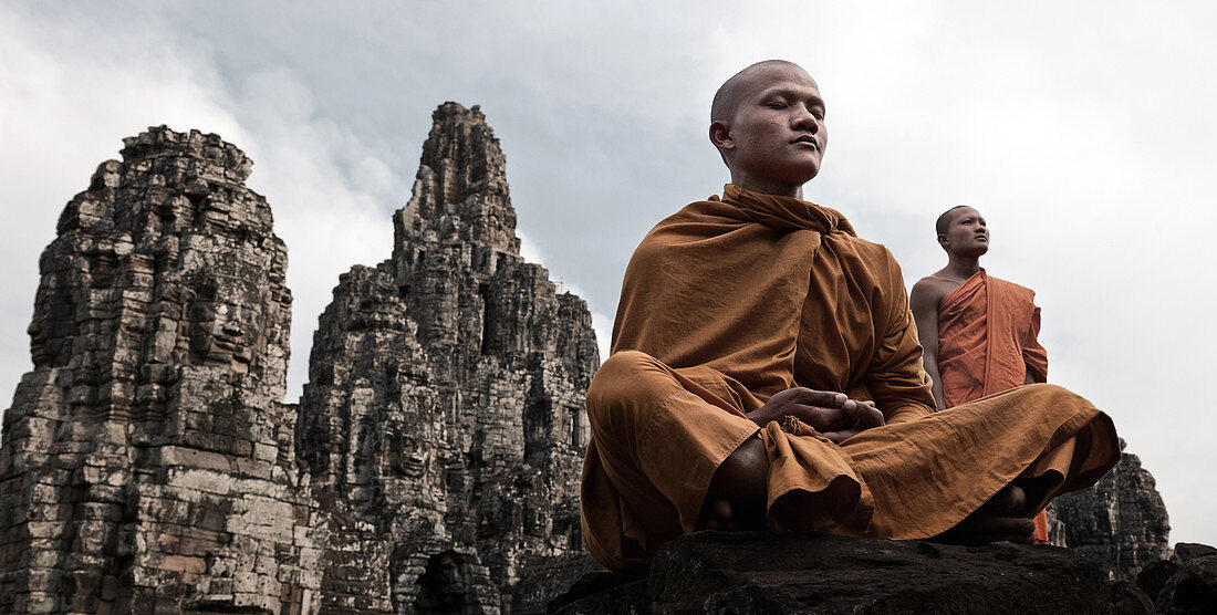 Siem Reap, Kambodscha - 19. Januar 2011: Ein Mönch steht hinter einem sitzenden und meditierenden Mönch in Angkor