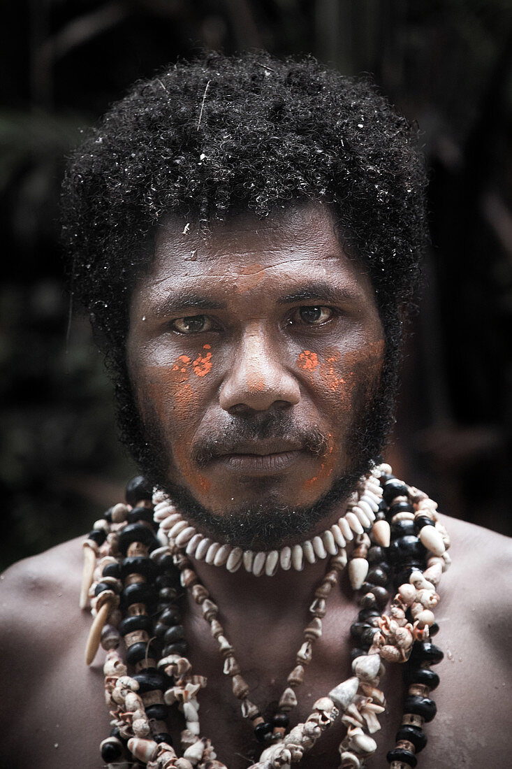Papua New Guinea - November 8, 2010: A man with tribal face painting and shell necklace.