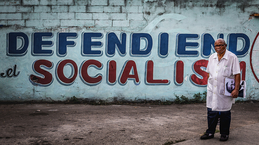 Cubans posing in front of a wall with political statements, Havana, Cuba
