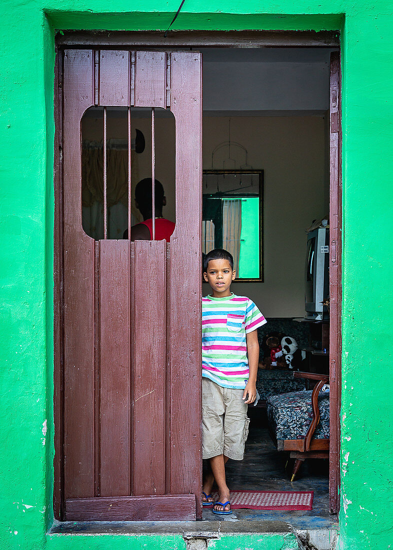 Cuban boy stands at the door, Camagüey, Cuba