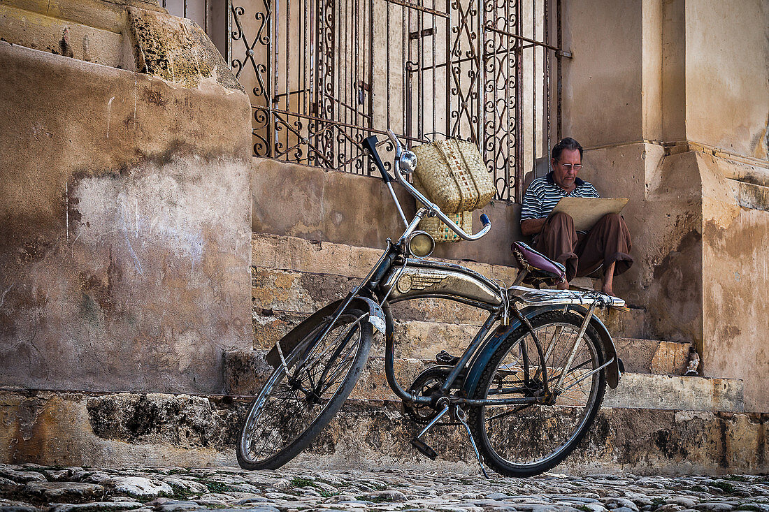 Künstler sitzt hinter seinem Rad und zeichnet die Stadt in Trinidad, Kuba