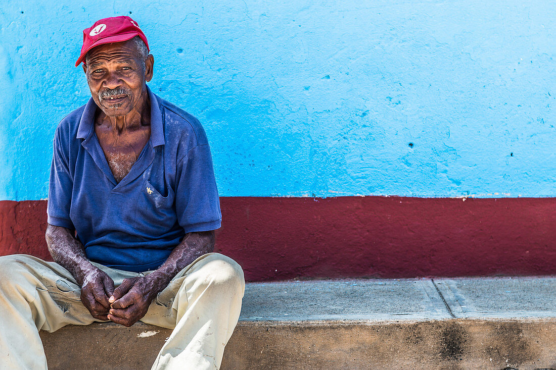 Kubaner sitzt an Wegrand in Trinidad, Kuba