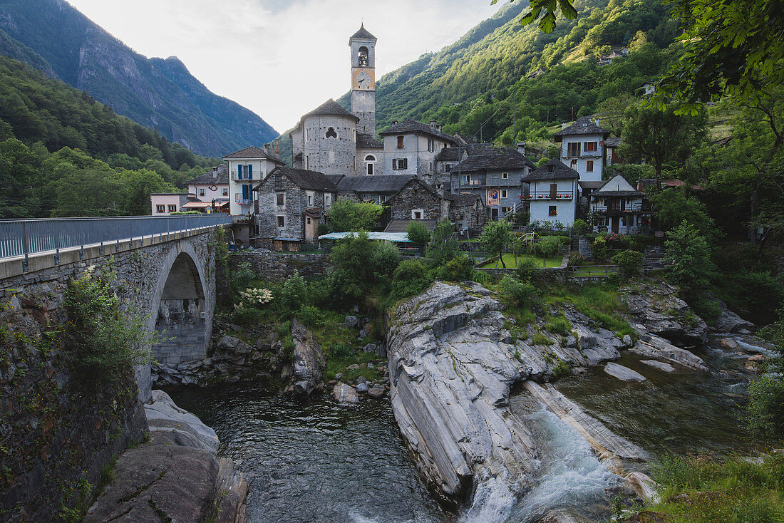 Bell tower by bridge and river in Ticino, Switzerland