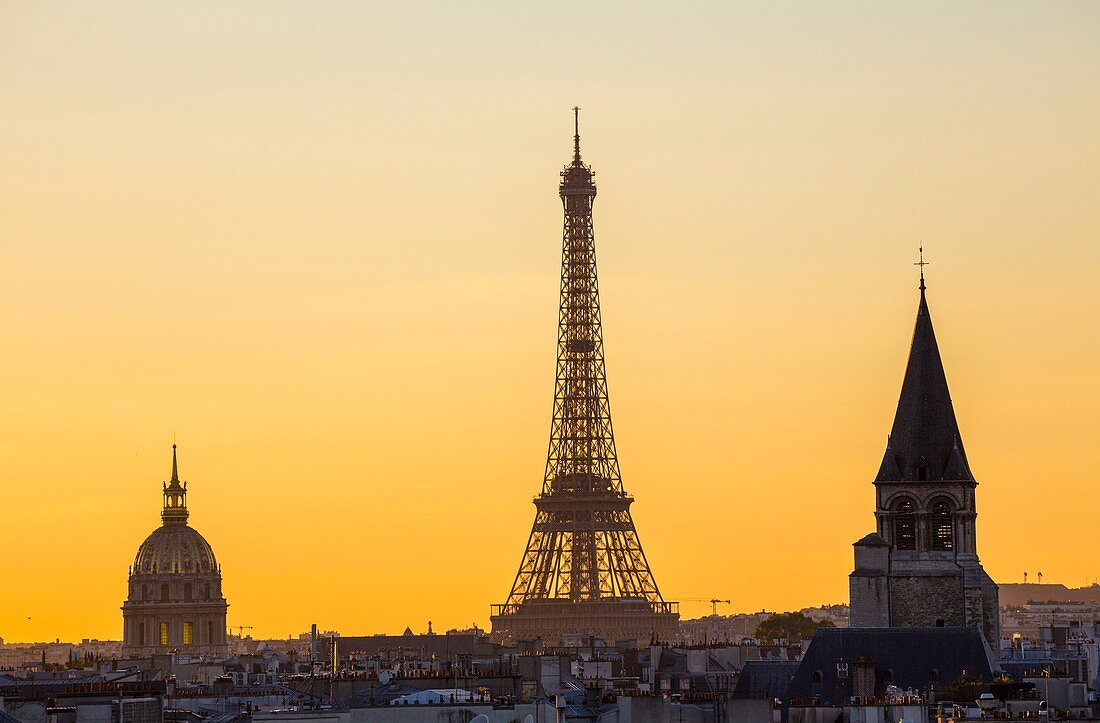 Frankreich, Paris, von der UNESCO zum Weltkulturerbe erklärtes Gebiet, der beleuchtete Eiffelturm (© SETE Illuminations Pierre Bideau), die Kuppel des Invalidendoms und der Glockenturm des Saint-Germain-des-Pres und die Dächern von Paris bei Sonnenuntergang