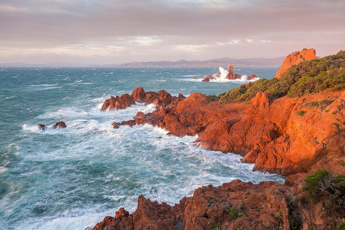 France, Var, Saint Raphael, heavy swell and high winds on the red cliffs of volcanic origin (rhyolite) of the Cap du Dramont, in background the tower of the ile d'Or