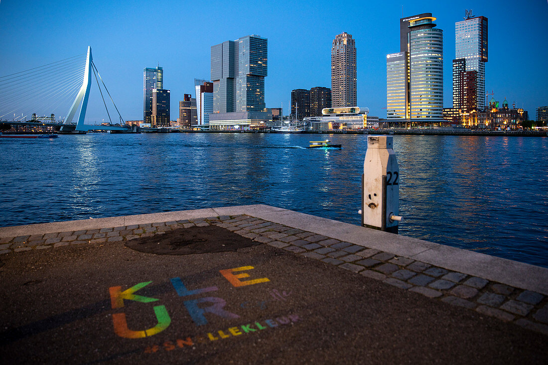 Blick während der Blauen Stunde über die Neue Maas auf die Erasmusbrücke und die Skyline am Cruise Terminal in Rotterdam, Niederlande