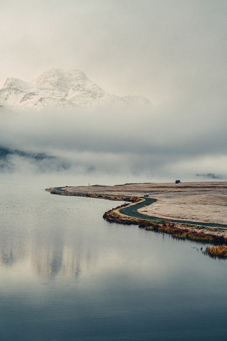 Shore of Lake Silvaplana in the fog at sunrise in the Upper Engadine, St. Moritz in the Engadine, Switzerland