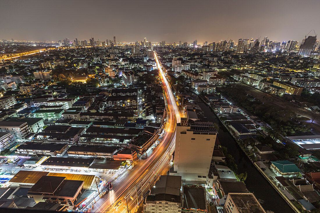 Blick über Wohnhäuser und Skyline in Upper Sukhumvit von Hochhaus bei Nacht, Bangkok, Thailand