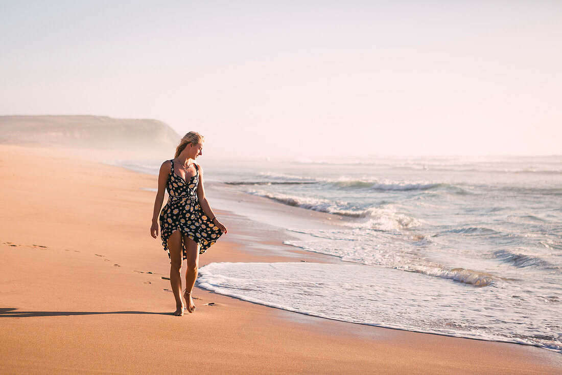 Frau in schwarzem Kleid am Strand