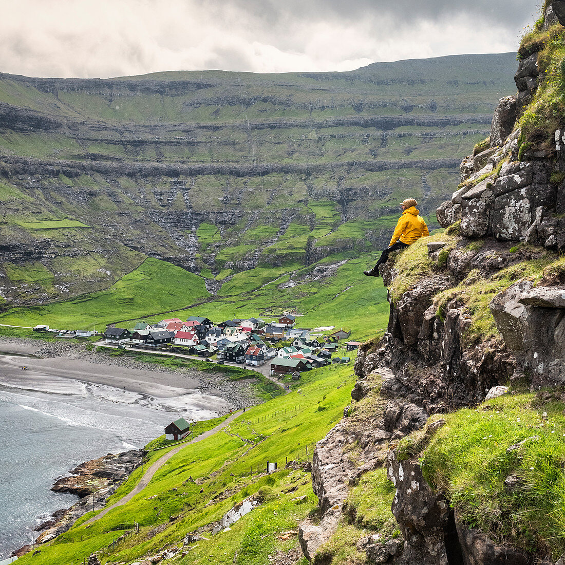 The hiker is admiring the little village of Tjornuvik, Streymoy island, Faroe Islands, Denmark, Europe