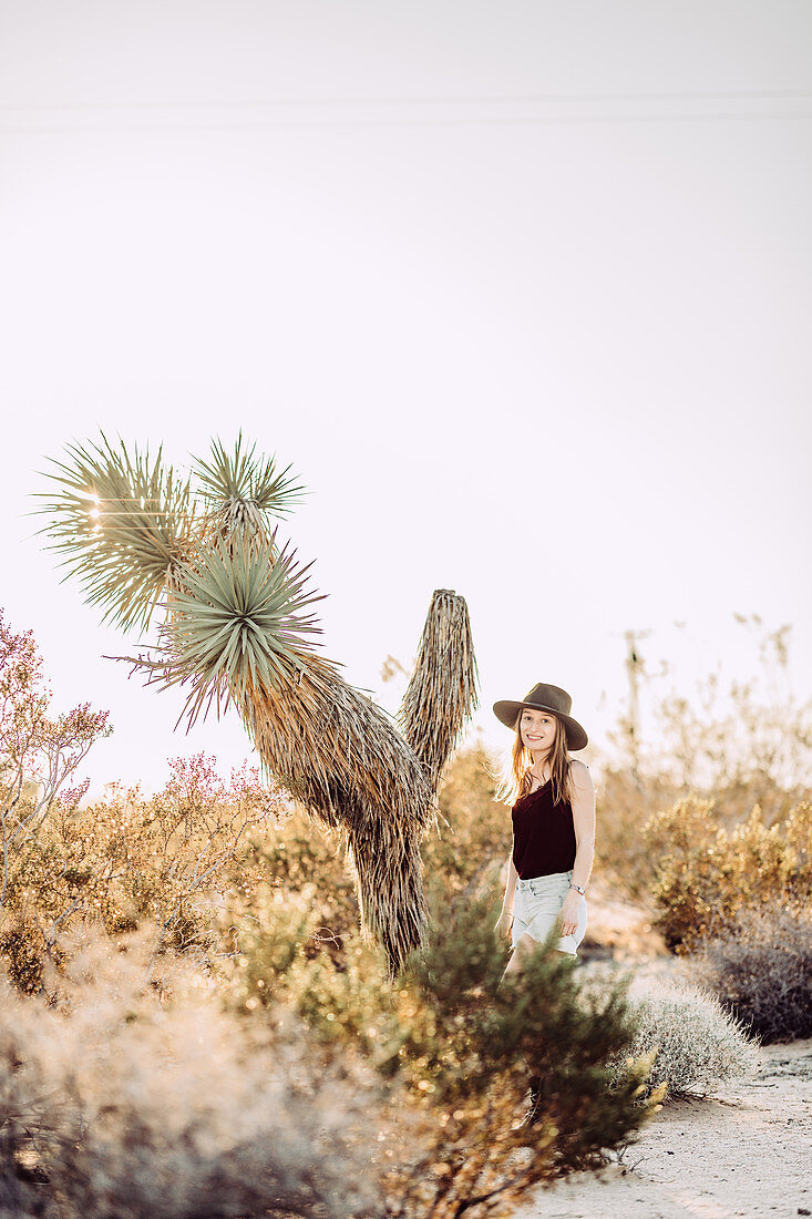 Frau steht neben Josuabaum im Joshua Tree National Park, Joshua Tree, Los Angeles, Kalifornien, USA, Nordamerika