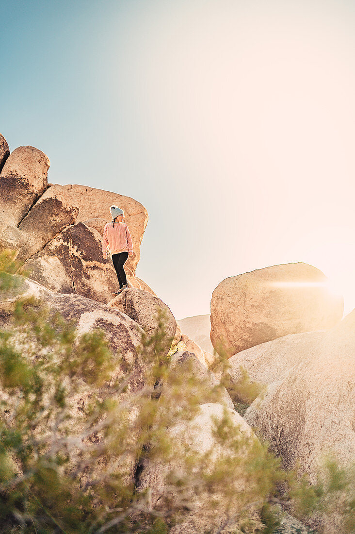 Woman hikes between rocks in Joshua Tree National Park, Los Angeles, California, USA, North America