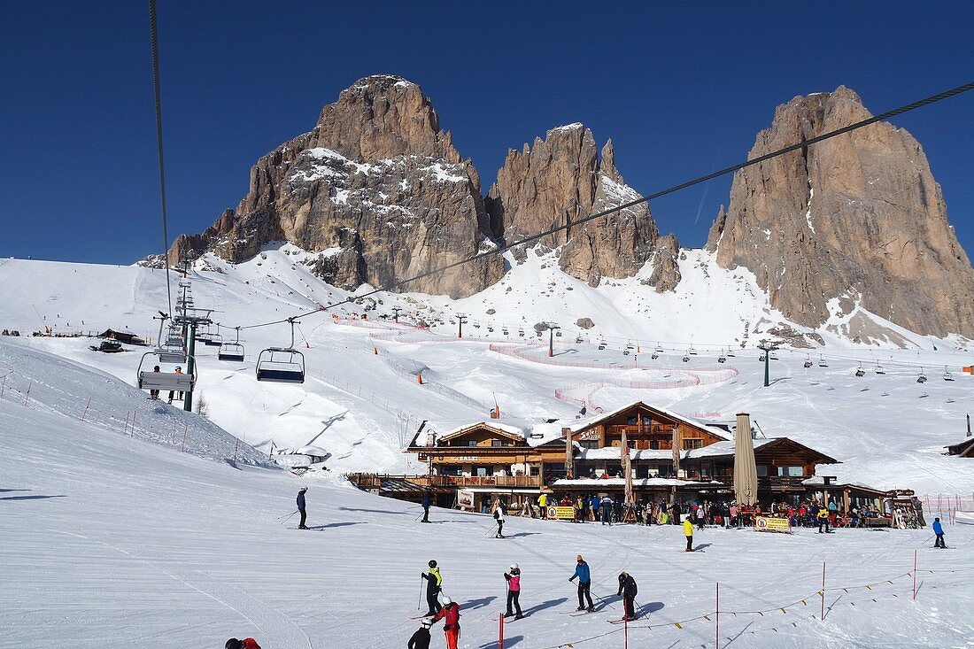 Ski under the Langkofel over Campitello, skier, ski slope, rock, ski hut, Dolomites, Trentino in winter, Italy