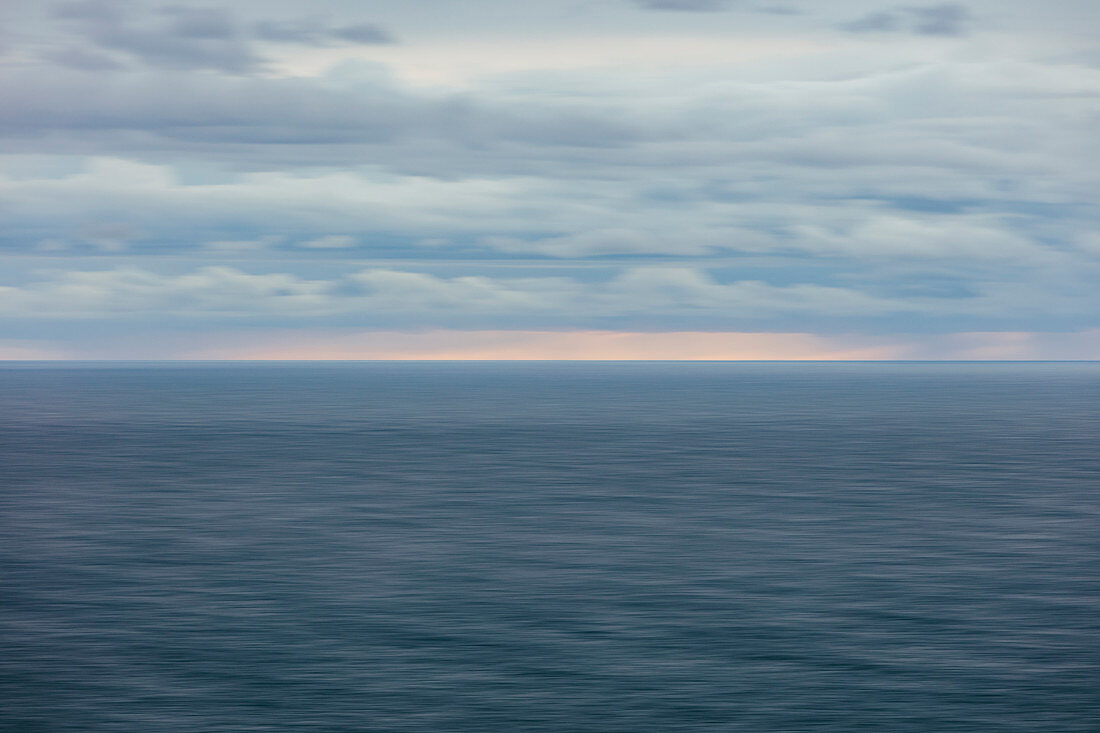 Blurred motion abstract of ocean, horizon and stormy sky at dusk