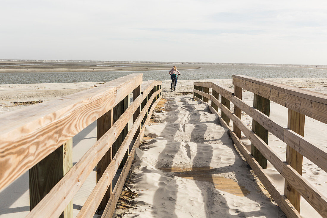 teen girl on her bike crossing bridge to the beach, St. Simon's Island, Georgia