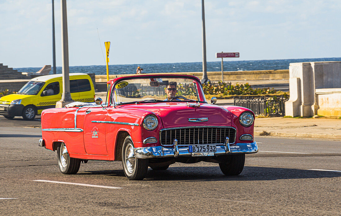 Roter Oldtimer an der Malecon - Promenade am Wasser. Altstadt von Havanna, Kuba