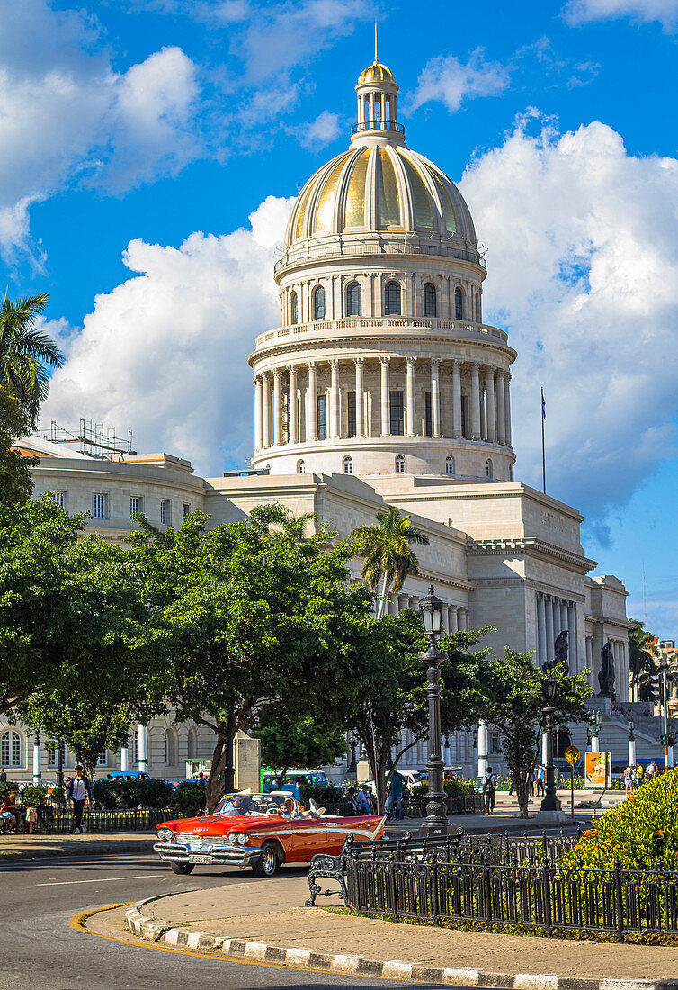 Lateral view from street with red classic car on Capitol, Old Havana, Cuba