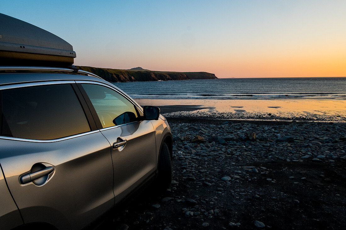 Am Strand parkendes Auto bei Sonnenuntergang, Küste von Pembrokeshire, Wales, Großbritannien