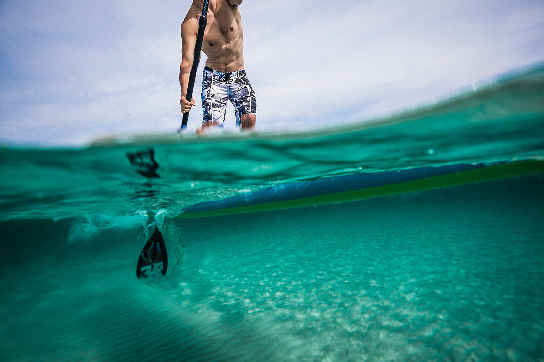 Person auf einem Paddle Board, Blick sowohl unter als auch über die Wasseroberfläche