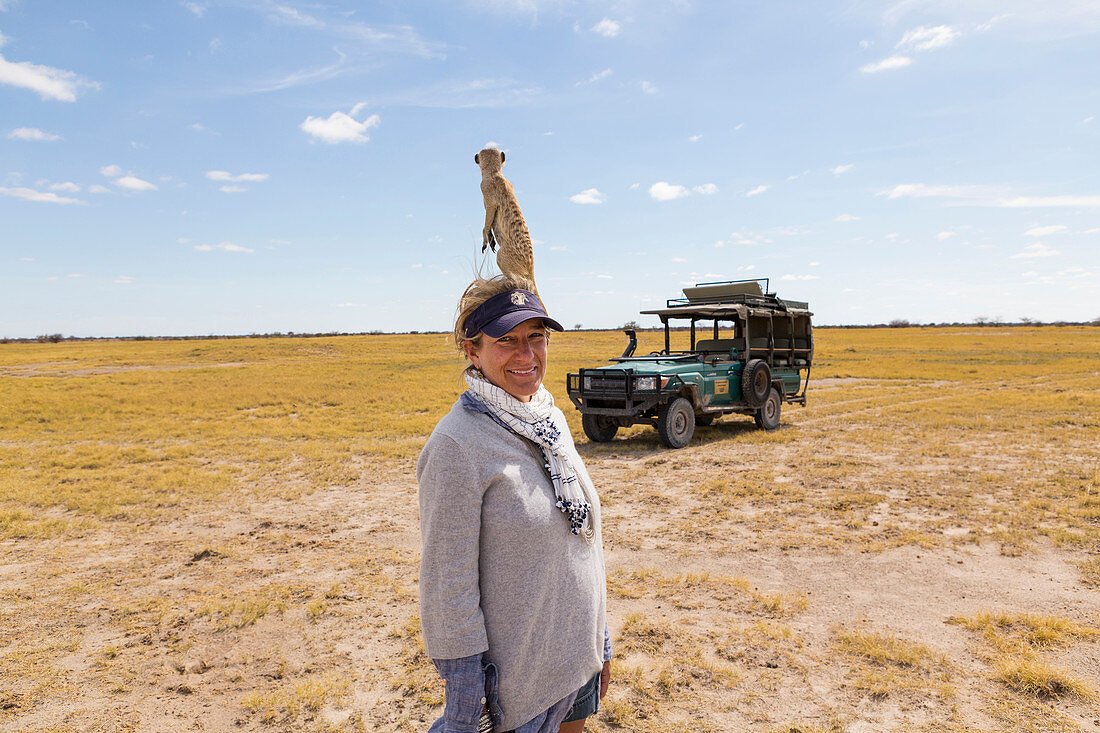 Eine Frau mit Erdmännchen auf der Schulter, Kalahari-Wüste, Makgadikgadi-Salzpfannen, Botswana