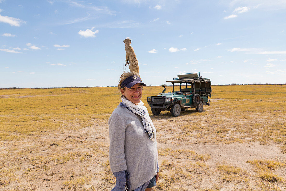 adult woman with Meerkat on her head, Kalahari Desert, Makgadikgadi Salt Pans, Botswana