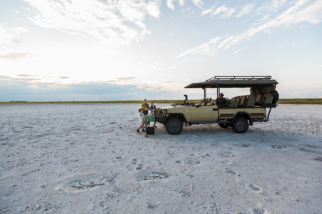 A safari vehicle parked in the salt pans landscape at dusk.