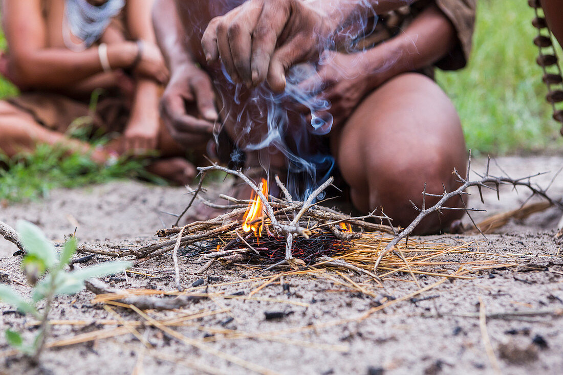 Mann vom San-Volk (Buschmann) beim Feuer machen, Botswana (Nahaufnahme)