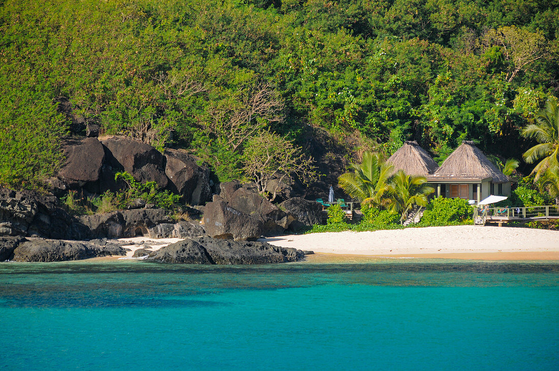 Traumstrand und Palmen mit kleinen Hütten eines Beach Resorts, Naviti Island, Fiji