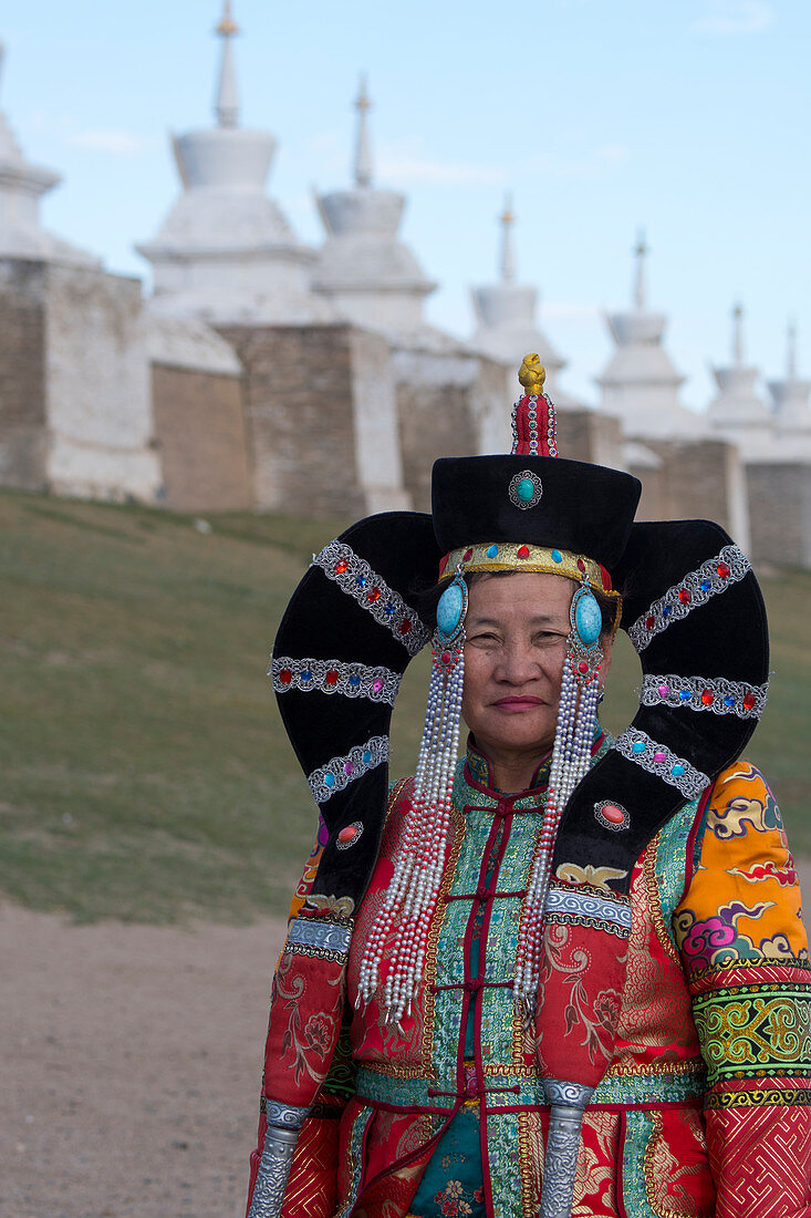 Eine mongolische Frau in historischer Tracht vor der Mauer mit Stupas, die das Kloster Erdene Dsuu umgeben, Kharakhorum (Karakorum), UNESCO-Weltkulturerbe, Mongolei