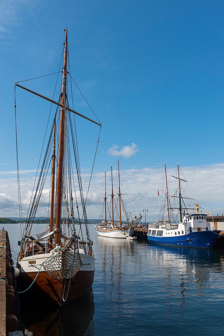 View of old sail boats docked in the harbor in front of the city hall in Oslo, Norway.