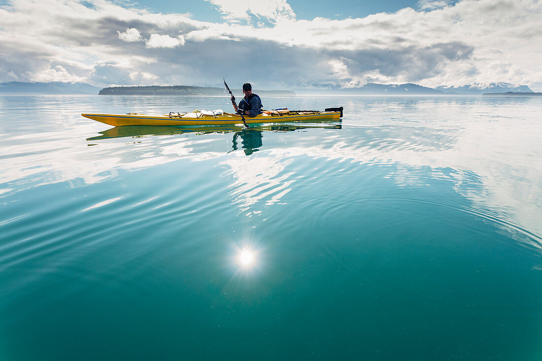 Mann unterwegs mit einem Kajak am sonnigen Tag vor der Küste von Alaska