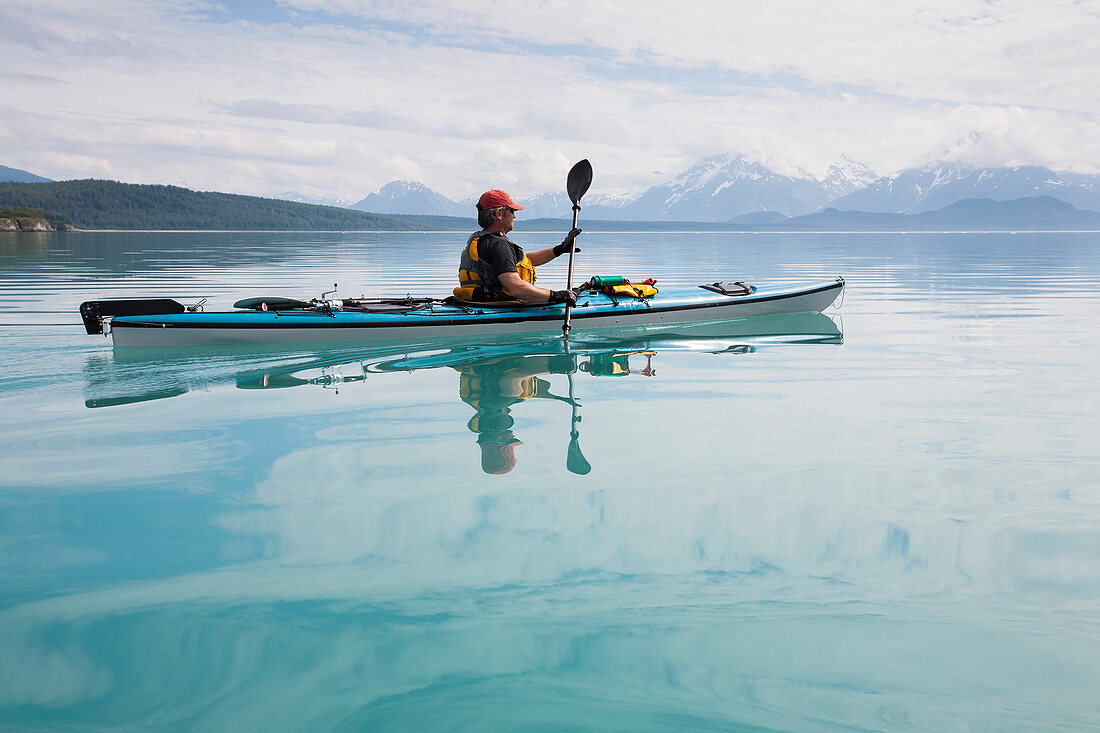 Man sea kayaking calm waters of an inlet in a national park.