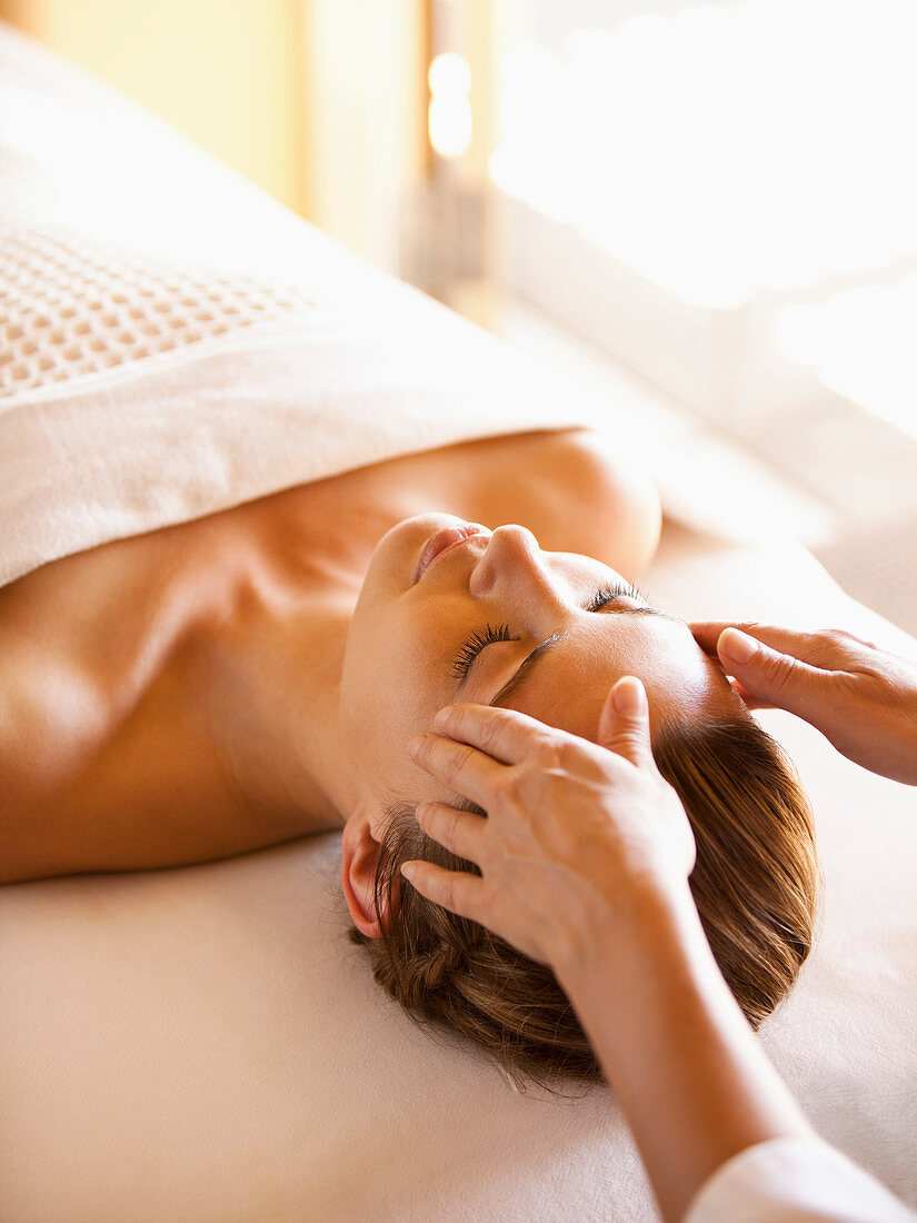 Woman lying on massage table receiving facial massage at a luxury spa in Napa Valley California