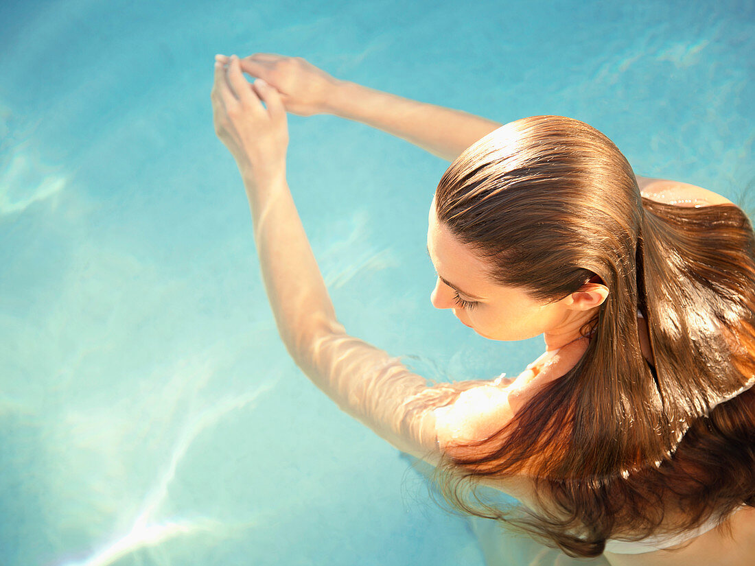 Rear overhead view of woman in water with arms outstretched in front of her
