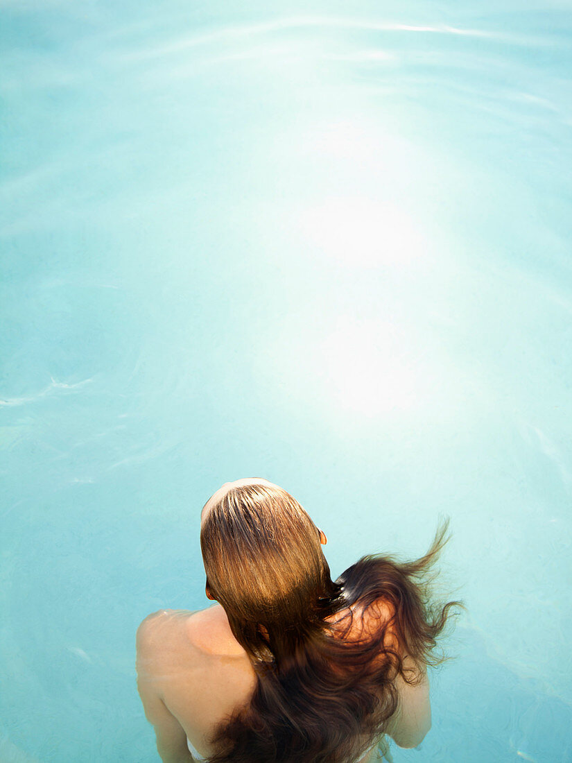 Rear overhead view of woman in water in swimming pool of a luxury resort in California
