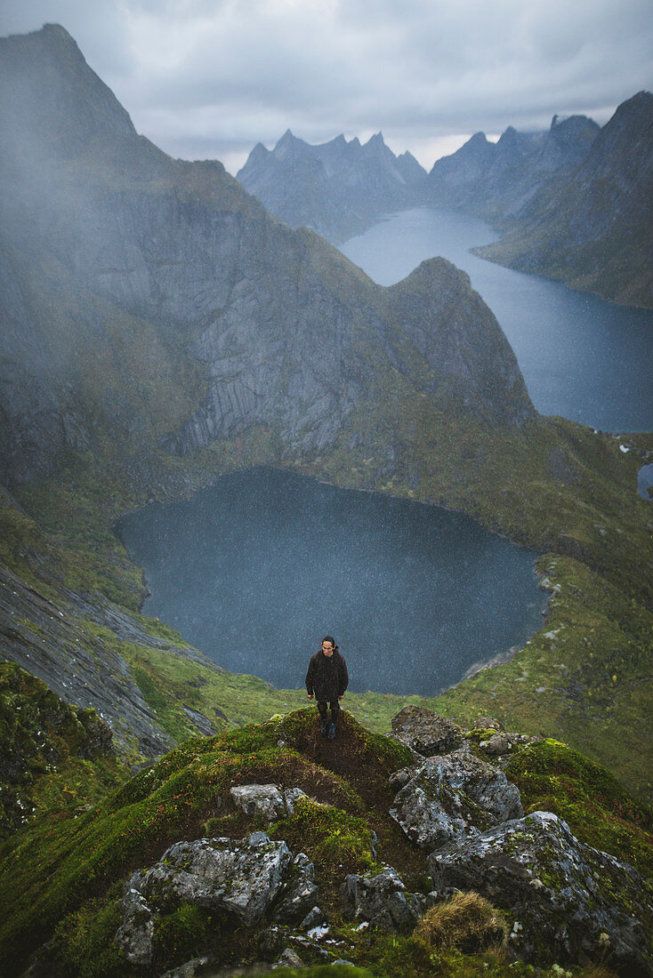 Norwegen, Lofoten, Reine, Mann auf dem Berg Reinebringen mit See und Fjord im Hintergrund