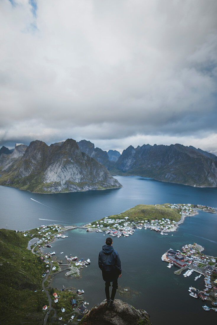 Norwegen, Lofoten, Reine, Mann schaut vom Reinebringen aus auf den Fjord
