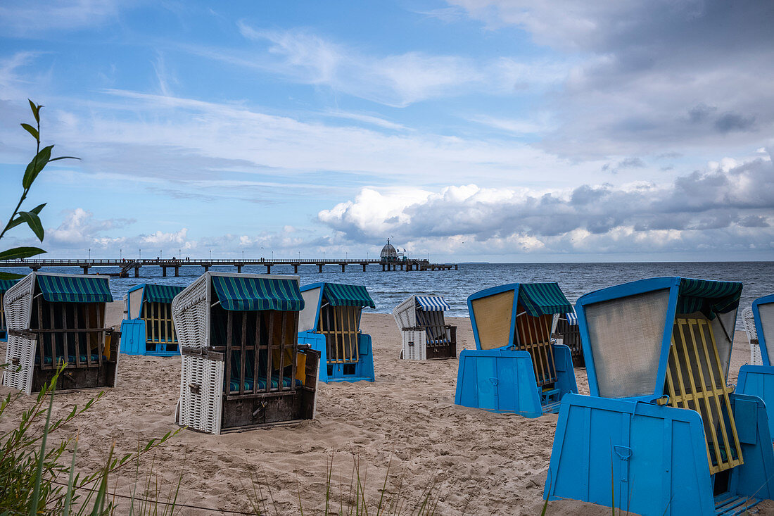Beach chairs on Usedom in the background the Zinnowitz pier, cloudy sky, restless sea, Usedom, Mecklenburg-Western Pomerania, Germany