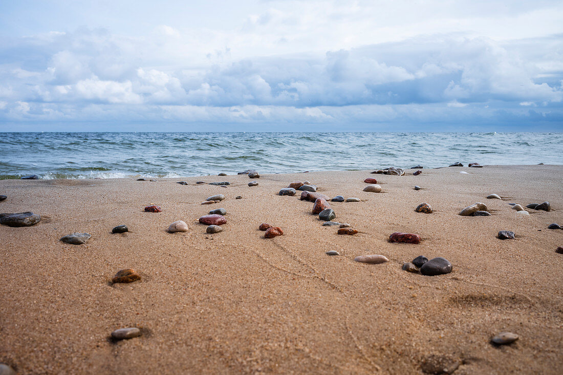 Baltic beach with washed up stones after a storm, rough sea and cloudy sky, Usedom, Mecklenburg-Western Pomerania, Germany