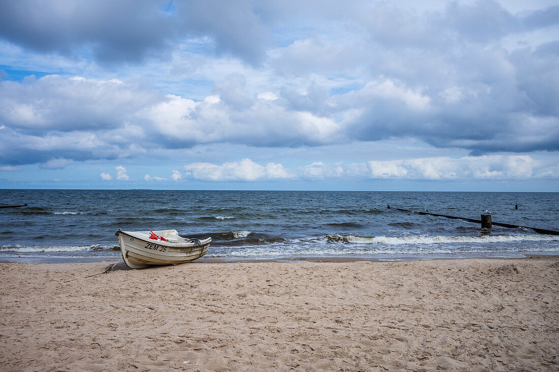 Fischerboot am Ostseestrand bei bewölktem dramatischem Himmel und rauer See, Usedom, Mecklenburg-Vorpommern, Deutschland