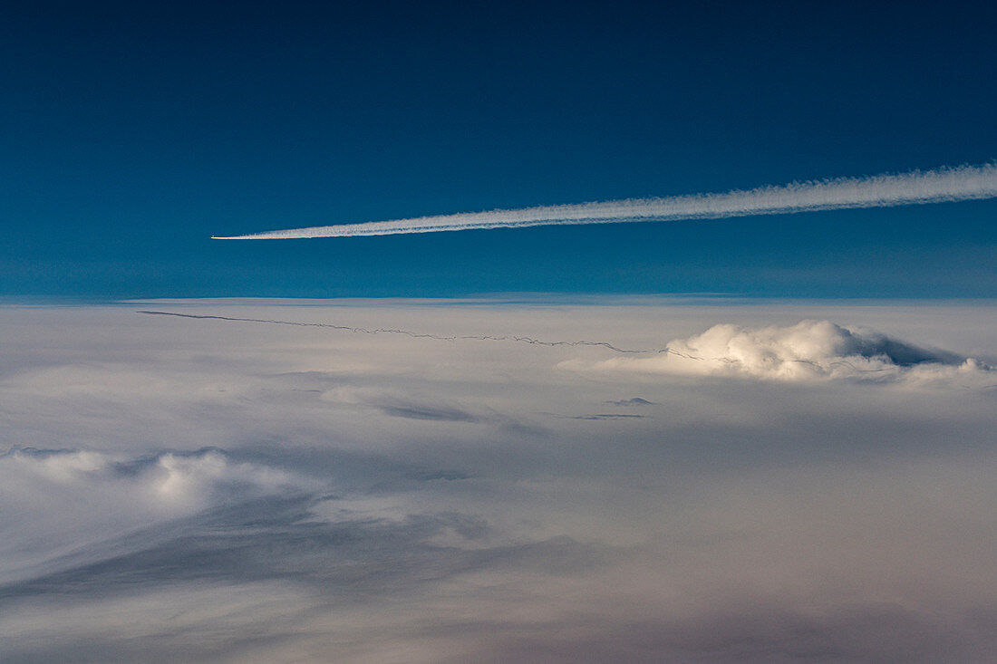 Flugzeuge mit Kondensstreifen über geschlossener Wolkendecke