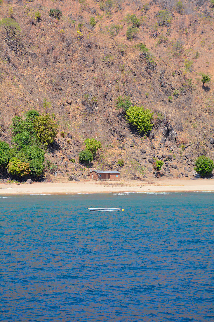 Malawi; Northern Region; Berglandschaft an der Küste bei Ruarwe; einsames Haus am Strand; vor der Küste ankert ein Fischerboot